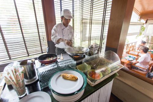 a chef preparing food on a counter in a kitchen at Andaman White Beach Resort - SHA Plus in Nai Thon Beach