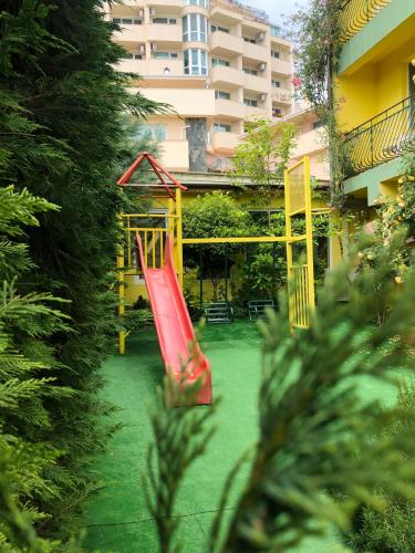 a playground with a red slide in a yard at Hotel Jambo in Golden Sands