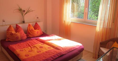 1 dormitorio con cama con sábanas de color naranja y ventana en Ferienwohnung am Bach, en Kreuzlingen