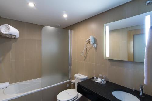 a bathroom with a toilet and a sink and a mirror at Hotel Quarteirasol in Quarteira