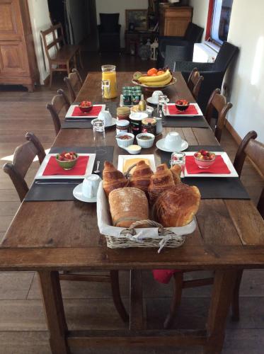 una mesa de madera con pan y bollería. en La Valse Lente, en Namur