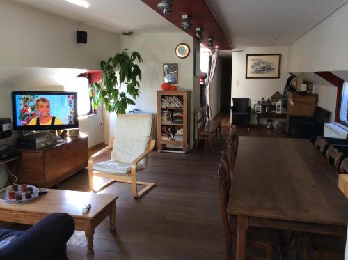 uma sala de estar com uma mesa de jantar e uma televisão em La Valse Lente em Namur