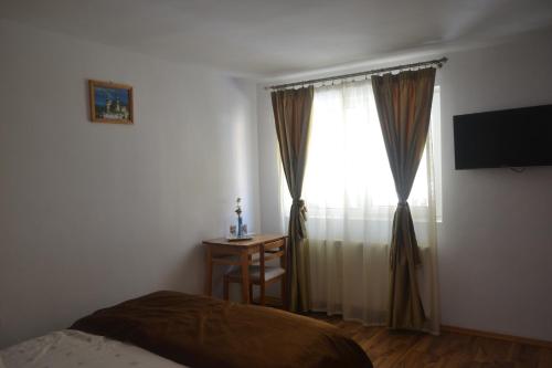 a bedroom with a bed and a window with a desk at Vila Pitty in Sinaia