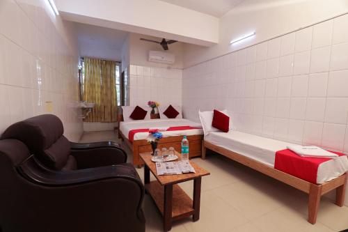 a room with two beds and a chair and a table at Laila Palace in Salem