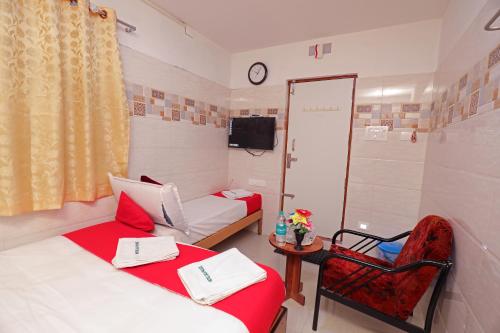 a room with two beds and a chair and a clock at Laila Palace in Salem