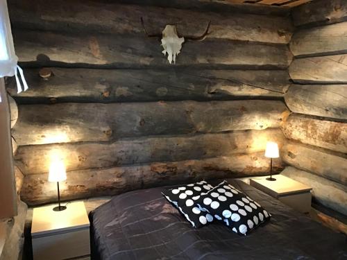 a bedroom with a log wall with a bed and two lamps at Rukan Villa Nuotta in Ruka