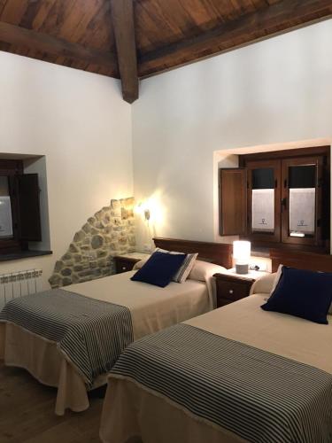 a bedroom with two beds and a stone wall at La Casa Vieja de Caneo - APARTAMENTOS RURALES 3 llaves in Luarca