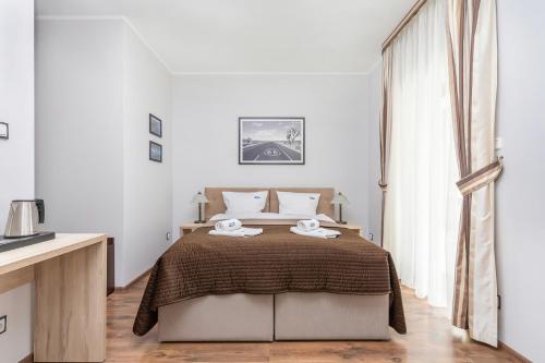 a white bedroom with a bed with two towels on it at Villa Baltic Dream in Międzyzdroje