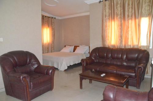 a living room with a bed and leather furniture at Hotel Ambassadors in Lomé