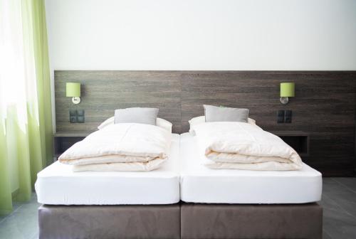 two beds with white sheets and pillows in a bedroom at eee Hotel Liezen in Liezen