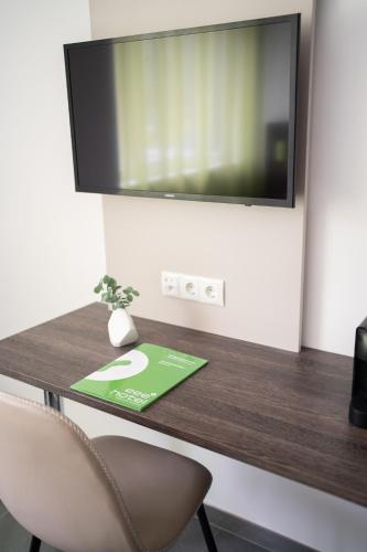 a desk with a television on a wall with a chair at eee Hotel Liezen in Liezen