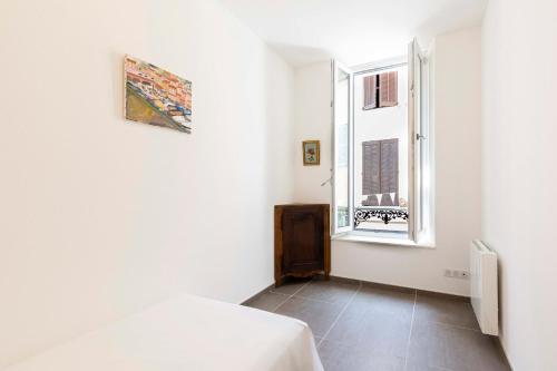 une chambre blanche avec un lit et une fenêtre dans l'établissement Maison de ville rue Fourmillière, à Antibes
