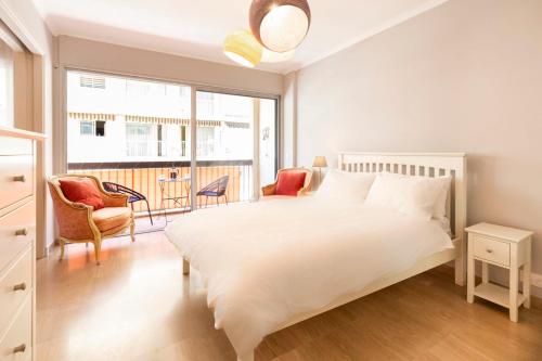 une chambre avec un grand lit blanc et deux chaises dans l'établissement Chez Philippe, à Antibes