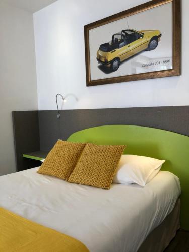 a bed with a green headboard and a yellow car under a picture at Les Tilleuls Montbeliard Sud Audincourt in Audincourt