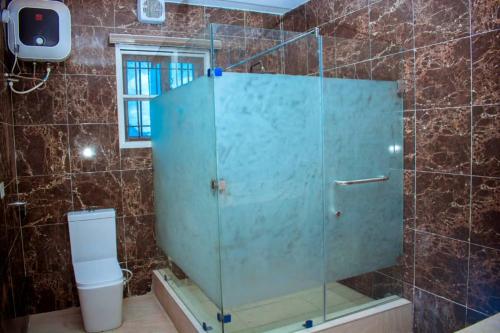 a glass shower in a bathroom with a toilet at Mexiloyd Luxury Rooms & Suites in Port Harcourt