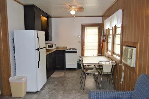 Il comprend une cuisine équipée d'un réfrigérateur blanc, d'une table et de chaises. dans l'établissement Baileys Sunset Cottages, à Baileys Harbor