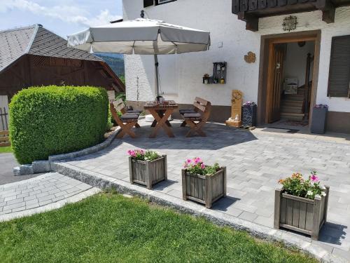 a patio with a table and an umbrella and some flowers at Haus Binder in Weissensee