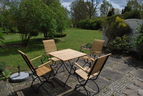 een houten tafel en vier stoelen in een tuin bij Jasmundhus in Neddesitz