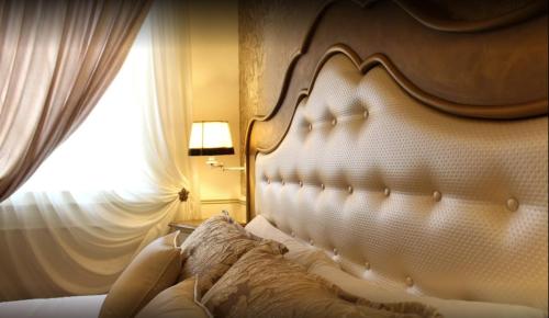 a bedroom with a bed with a large headboard and a window at Relais Colle San Pietro in Verona