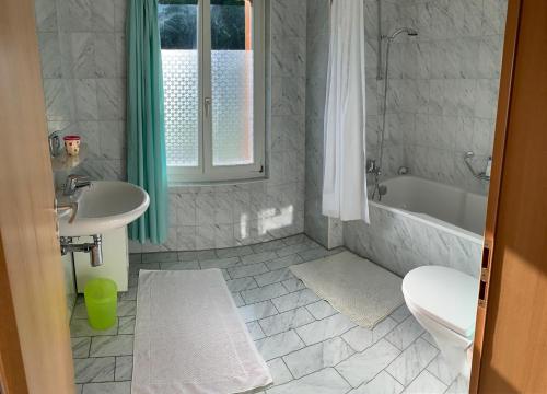 ein Badezimmer mit einem Waschbecken, einer Badewanne und einem WC in der Unterkunft B&B Maetteli in Hasliberg