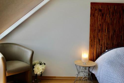 a bedroom with a chair and a candle on a table at Royal Confort in Bayeux