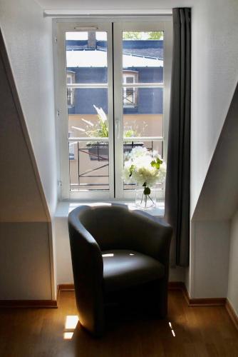 une chaise noire assise devant une fenêtre dans l'établissement Royal Confort, à Bayeux