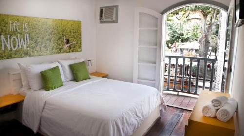 a bedroom with a white bed and a balcony at Lulu Pousada Buzios in Búzios