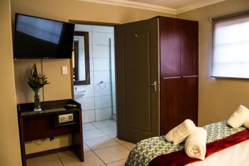 a bathroom with a bed and a television and a tub at APS Guesthouse in Windhoek