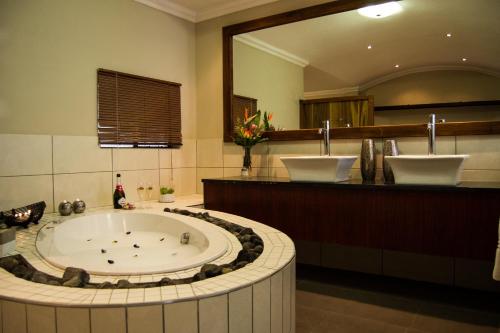 APS Guesthouse في ويندهوك: حمام مع حوض كبير ومرآة كبيرة