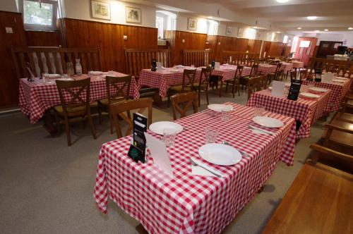 a restaurant with red and white checkered tables and chairs at Fehér Hajó Panzió és Vendéglő in Győr