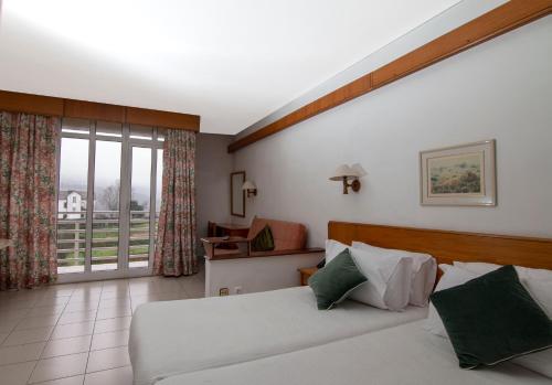 a bedroom with two beds and a large window at Pantanha Apartment by Trip2Portugal in Nelas