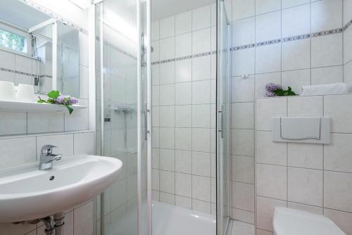 La salle de bains blanche est pourvue d'un lavabo et d'une douche. dans l'établissement Gästehaus Lazarus, à Berlin