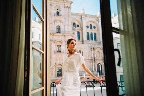 a woman in a white dress looking out a window at Molina Lario in Málaga