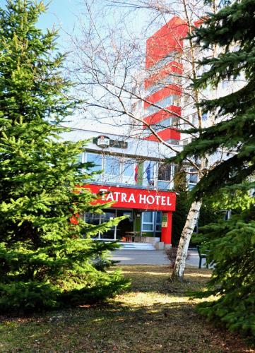 a hotel with a red sign in front of a building at Tatra Hotel in Poprad