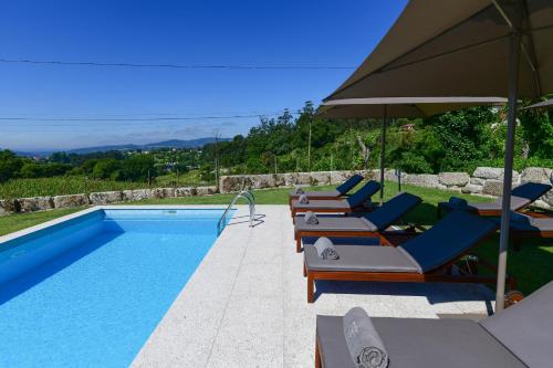 a swimming pool with lounge chairs and an umbrella at Vila Coura in Amarante