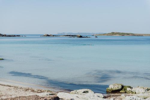 
a beach with a body of water and a lighthouse at Hotel Honucai in Colònia de Sant Jordi
