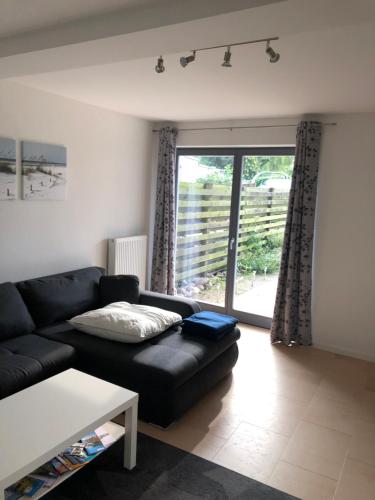 a living room with a black couch and a large window at Ferienwohnung Zur Auszeit Kontorhaus Malchow in Malchow