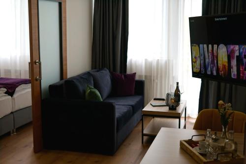 a living room with a blue couch and a table at DIWOTEL by Trip Inn Frankfurt Airport Dreieich in Dreieich