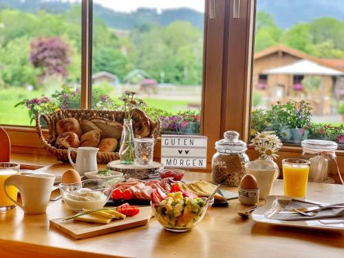une table avec de la nourriture pour le petit-déjeuner sur une table avec une fenêtre dans l'établissement Gästehaus "Zur Schmiede", à Wertach