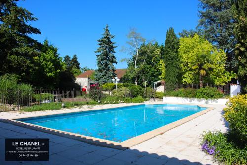 a swimming pool with blue water in a yard at Hôtel Restaurant Le chanel in Villieu