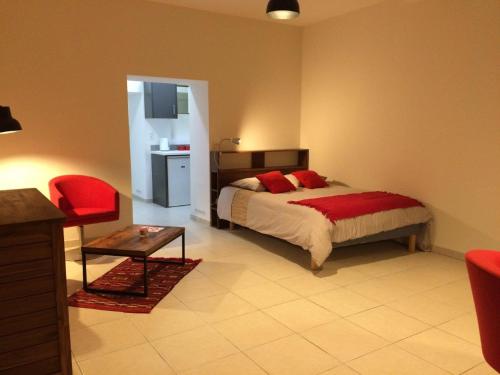 ein Schlafzimmer mit einem Bett und einem roten Stuhl in der Unterkunft Le Studio du Château in Auriac-sur-Vendinelle
