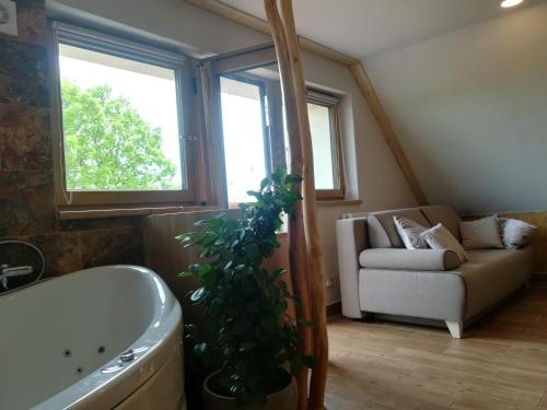 a bathroom with a tub and a couch and a plant at Apartmán Life in Nature in Jaronice