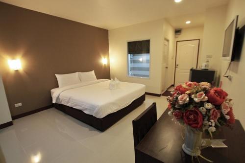 una habitación de hotel con una cama y flores en una mesa en Panwalee Hotel en Khon Kaen