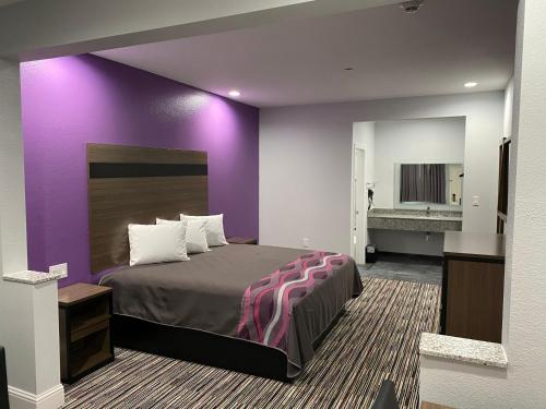 Habitación de hotel con cama y pared púrpura en Palace Inn Crosby, en Crosby