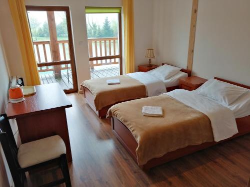 um quarto de hotel com duas camas e uma mesa e uma secretária em Restauracja Teo em Cieszków