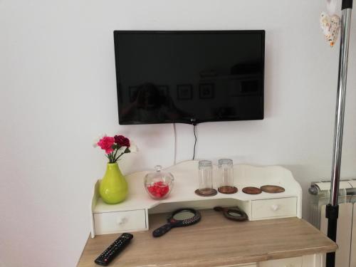 TV en la pared con una mesa con magdalenas en Moradia no Seixal Ericeira en Ericeira