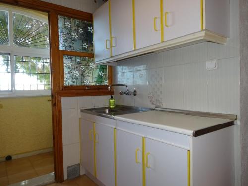 a kitchen with white cabinets and a sink and a window at Casa Mediterráneo in La Marina
