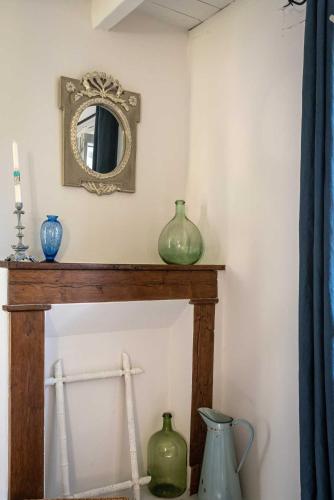 deux vases assis sur un manteau avec un miroir dans l'établissement au Mas de Garet - Chambre d'hotes de Charme, à Pinsac