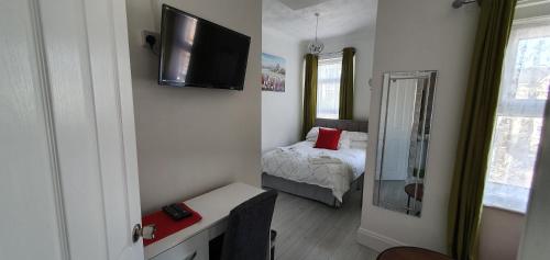 a small bedroom with a bed and a television on the wall at Holly Lodge in Weston-super-Mare