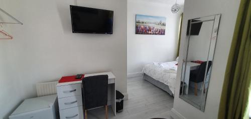 a bedroom with a bed and a desk and a television at Holly Lodge in Weston-super-Mare